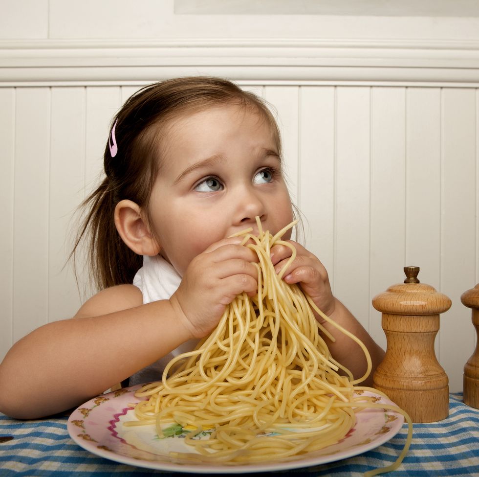 niña comiendo pasta con las manos