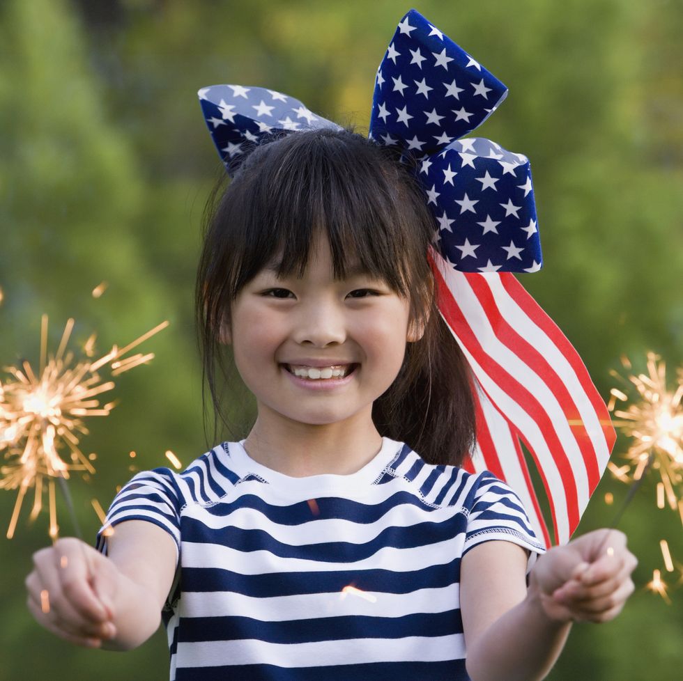 asian girl holding sparklers on fourth of july
