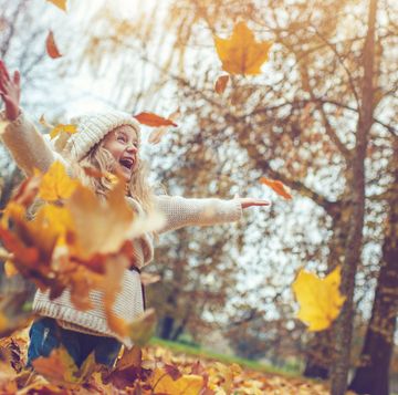 fall quotes kid in the woods with arms out wide and fall leaves falling around her