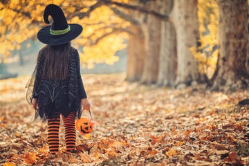 little girl in witch costume having fun on halloween trick or treat
