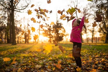 little girl jumping in falling leaves