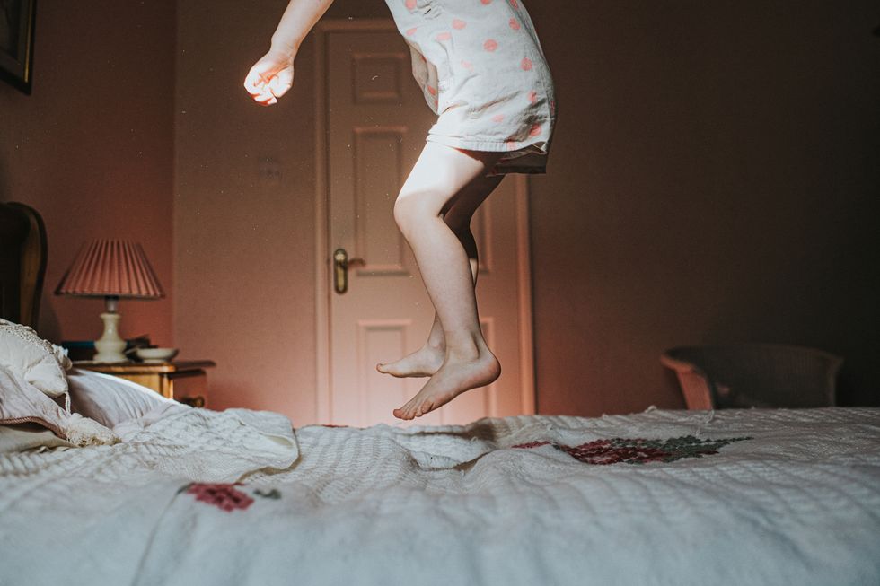 little girl jumping on an old fashioned bed