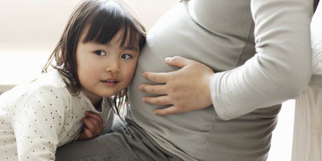 Little girl listening to pregnant mother's abdomen