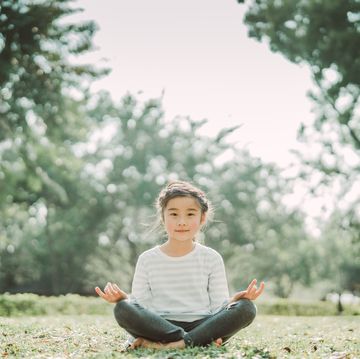 little girl practicing yoga joyfully on lawn
