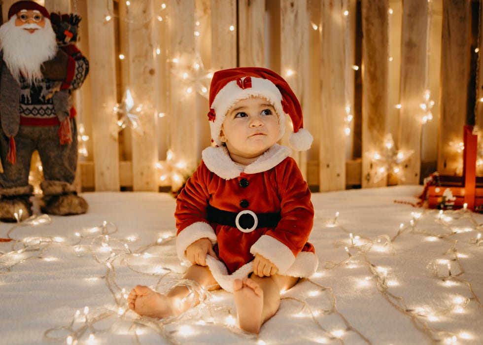 niña sentada vestida de santa claus con luces