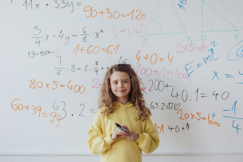 little girl standing in front of school board, mathematic class