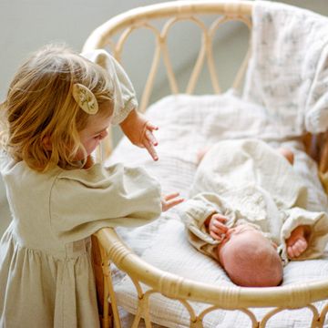 hermana mayor jutando con hermana pequena cuna mimbre