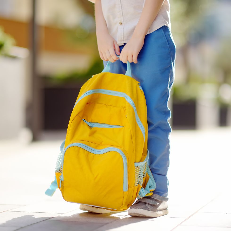 little student with a backpack on the steps of the stairs of school building