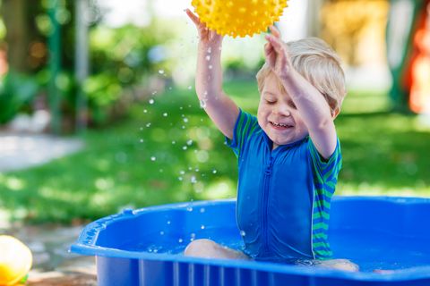 Little toddler boy having fun with splashing water in summer