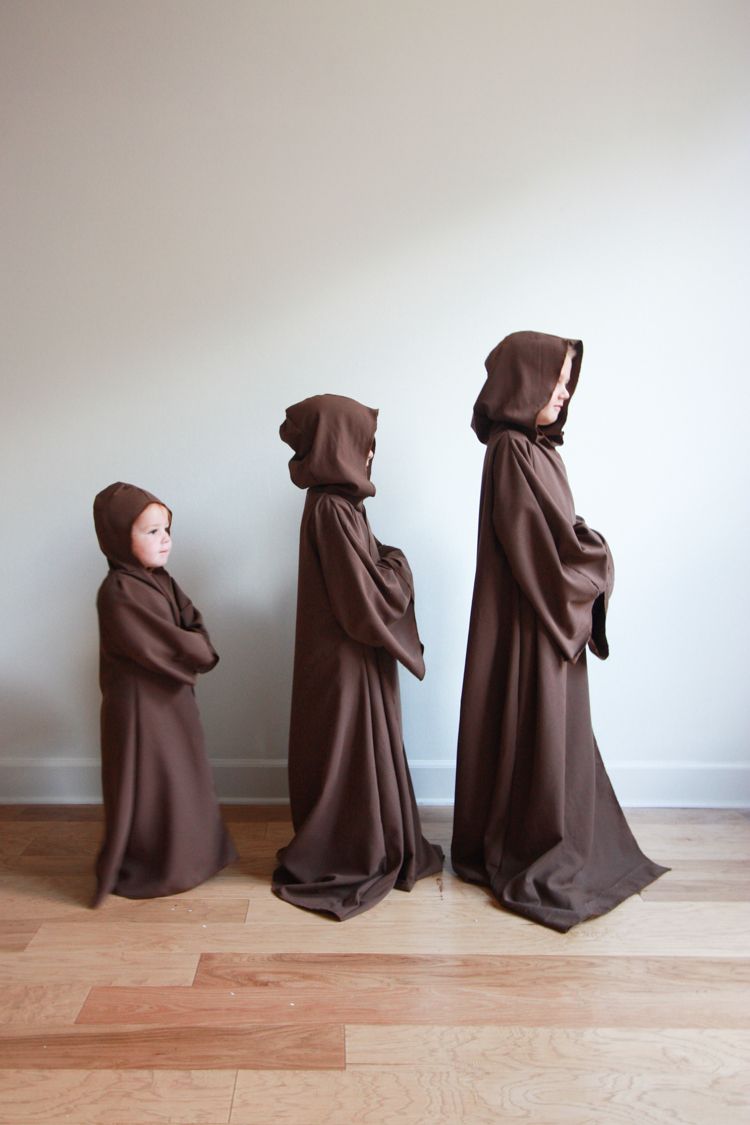 three kids dressed in brown hooded jedi robes walking across a wood floor only the smallest child's face is fully visible