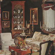living room filled with antiques, floral sofa, taper candles, china, dog portraits