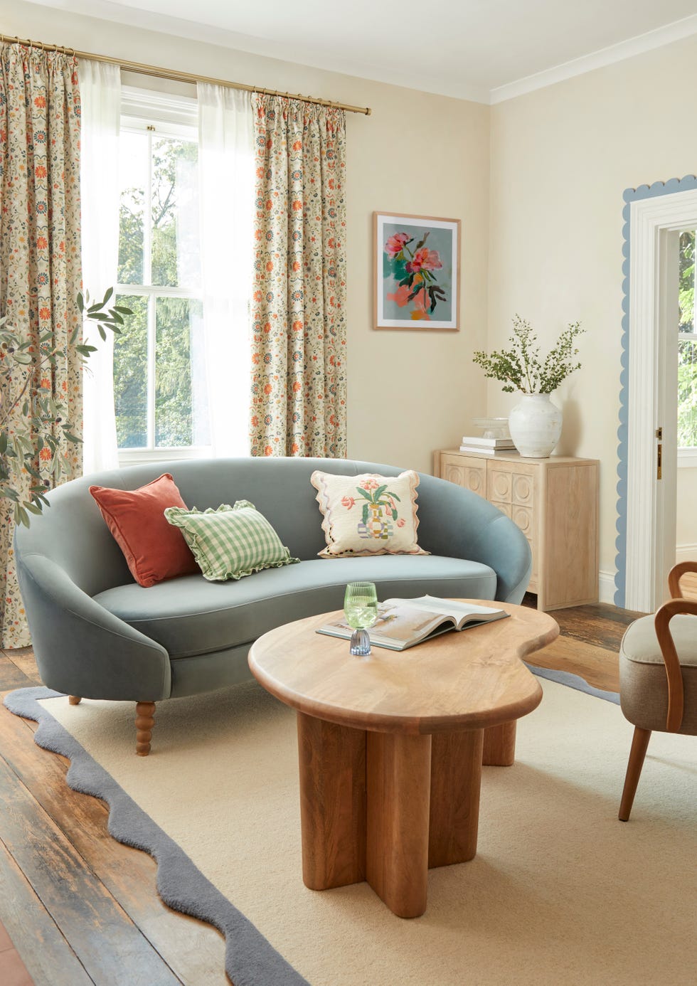 floral curtains alongside a curved sofa and curved coffee table in living room