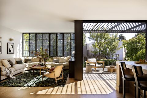 1920s spanish colonial in san francisco designed by regan baker design and landscape architect terremoto great room sliding steel and glass doors disappear when open, connecting the kitchen directly to the terrace and backyard sofa custom, franciscan interiors in kravet fabric rug alexander mcqueen, the rug company sconce philippe malouin for roll  hill, the future perfect coffee table nickey kehoe armchair mecox in kneedler fauchère leather outdoor chair design within reach cofee table rh side table dunkirk