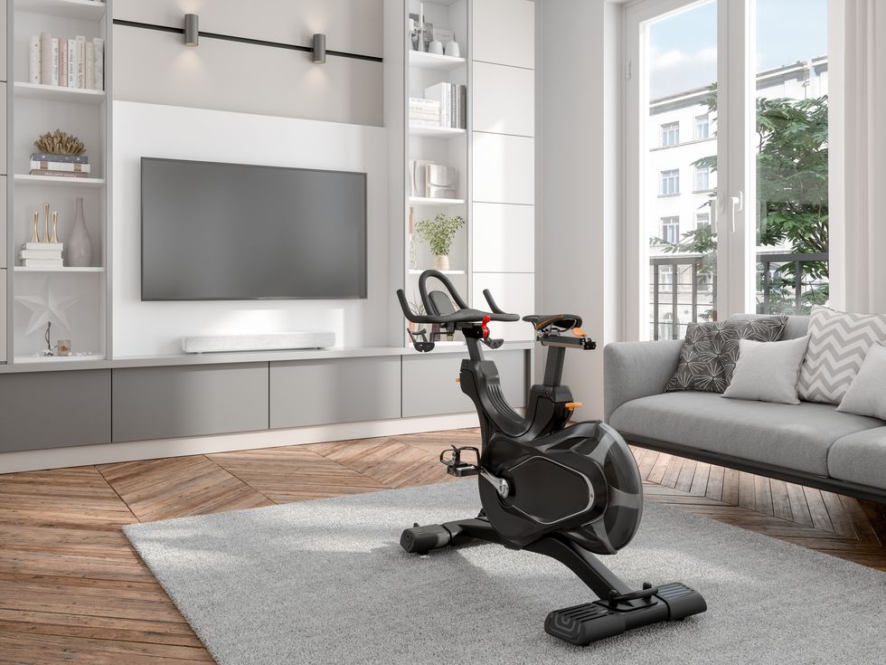 living room interior with exercise bike, sofa and television set exercising on tv at home