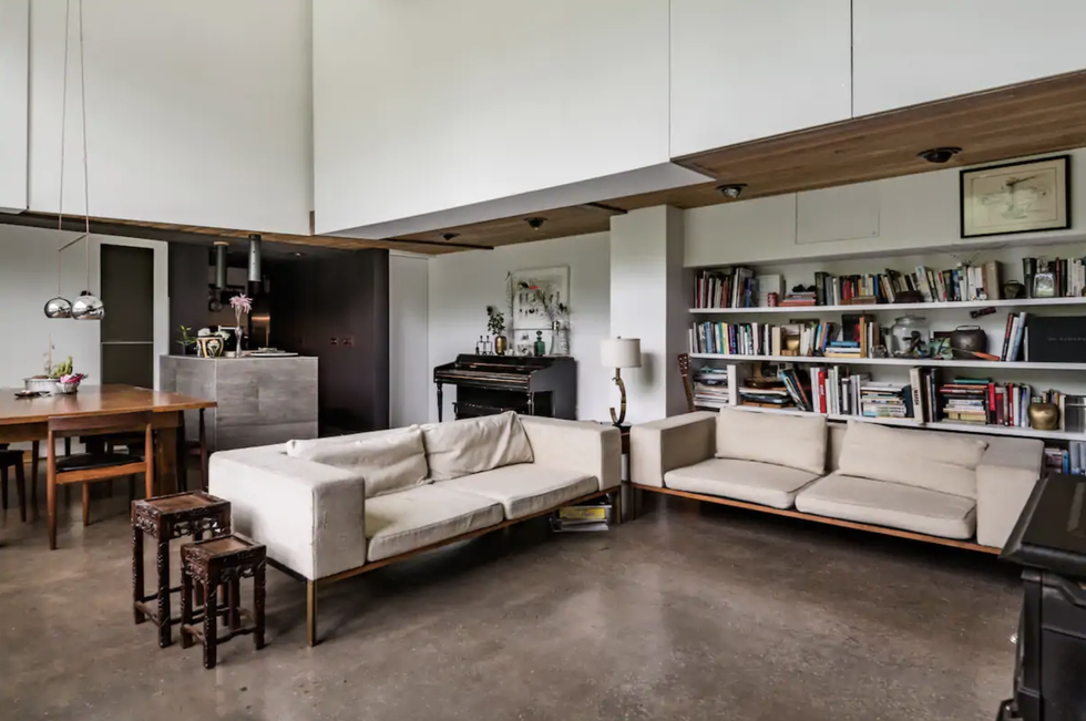 living room with couches, bookshelves, a piano, and fireplace in the woodstock estate