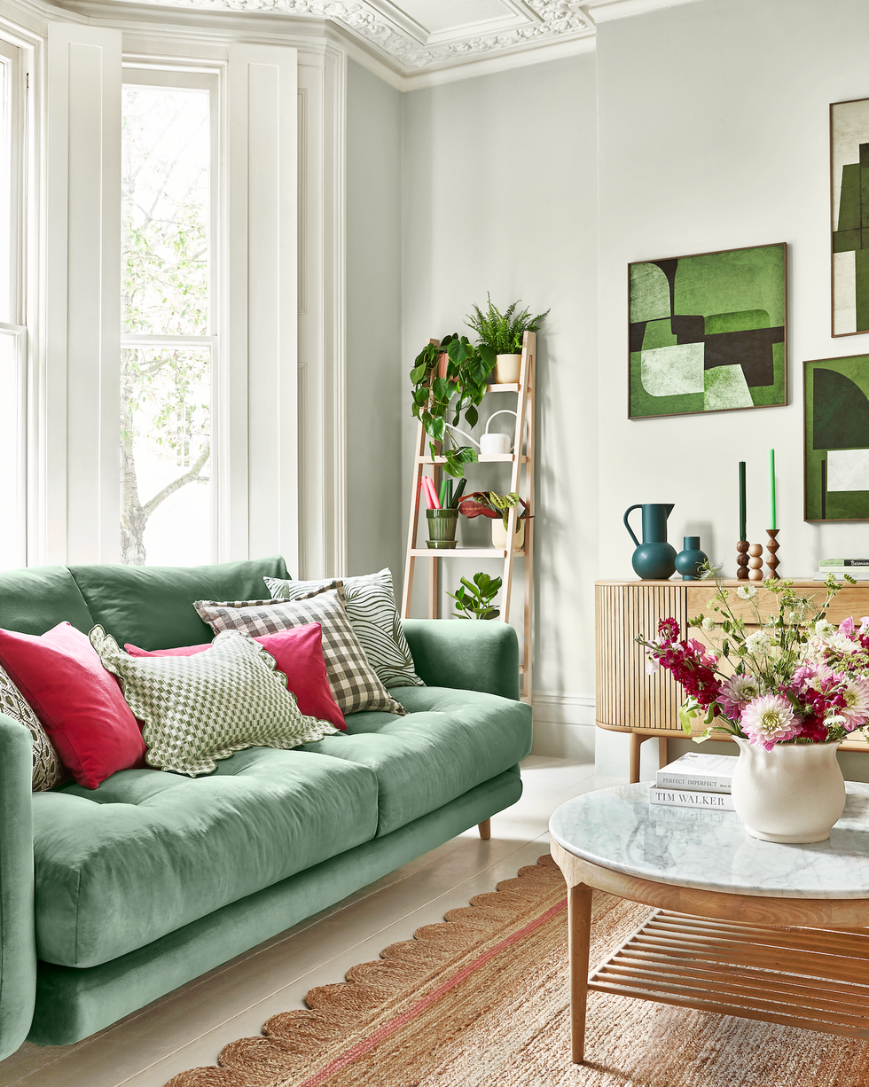 living room with green sofa, scalloped jute rug, oak sideboard and ladder shelf for plants
