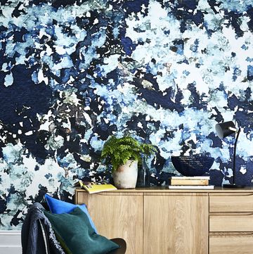 blue patterned wallpaper and blue and white patterened carpet with a wooden side cabinet bold impressiona streamlined sideboardcontrasts with a denselypatterned wall
