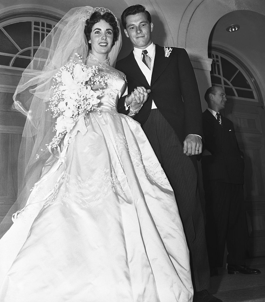 original caption 561950 beverly hills, ca  mr and mrs conrad hilton jr, pause on the steps of the church of the good shepherd here after their wedding the bride is the former elizabeth taylor, popular hollywood actress, and the groom is the son of the well known hilton hotel family