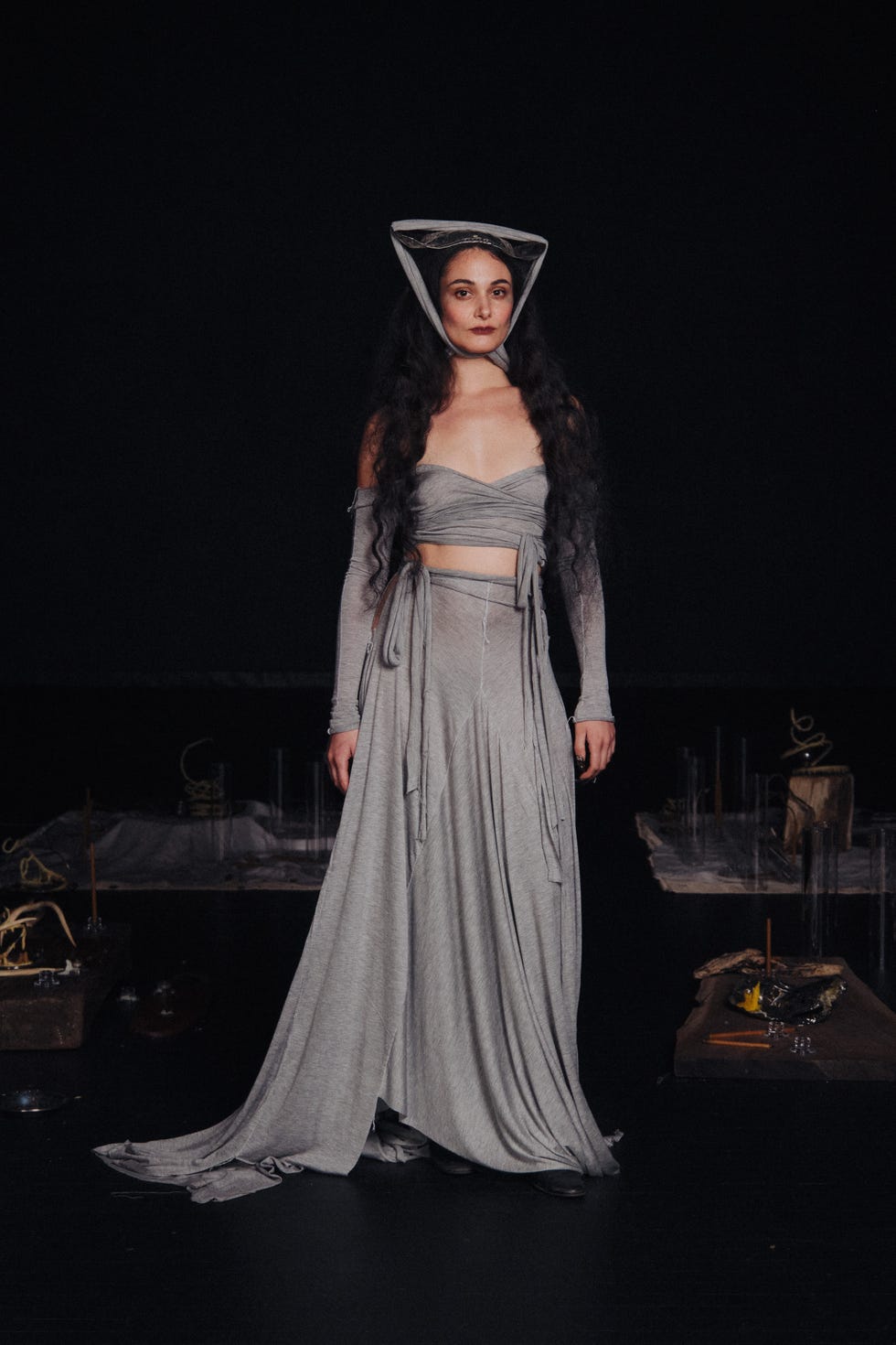 Una persona vestida con un traje gris se encuentra en un entorno oscuro.