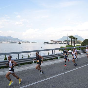 a group of people running on a road by a body of water
