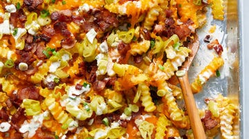 crinkle fries on a sheet pan topped with melted cheese, bacon, ranch, and banana peppers