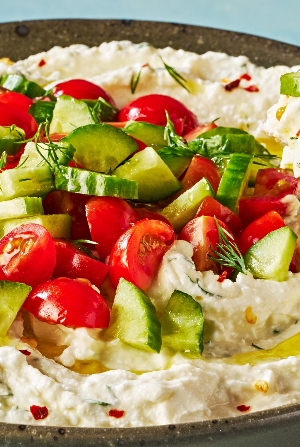 feta dip in a bowl topped with tomatoes and cucumber