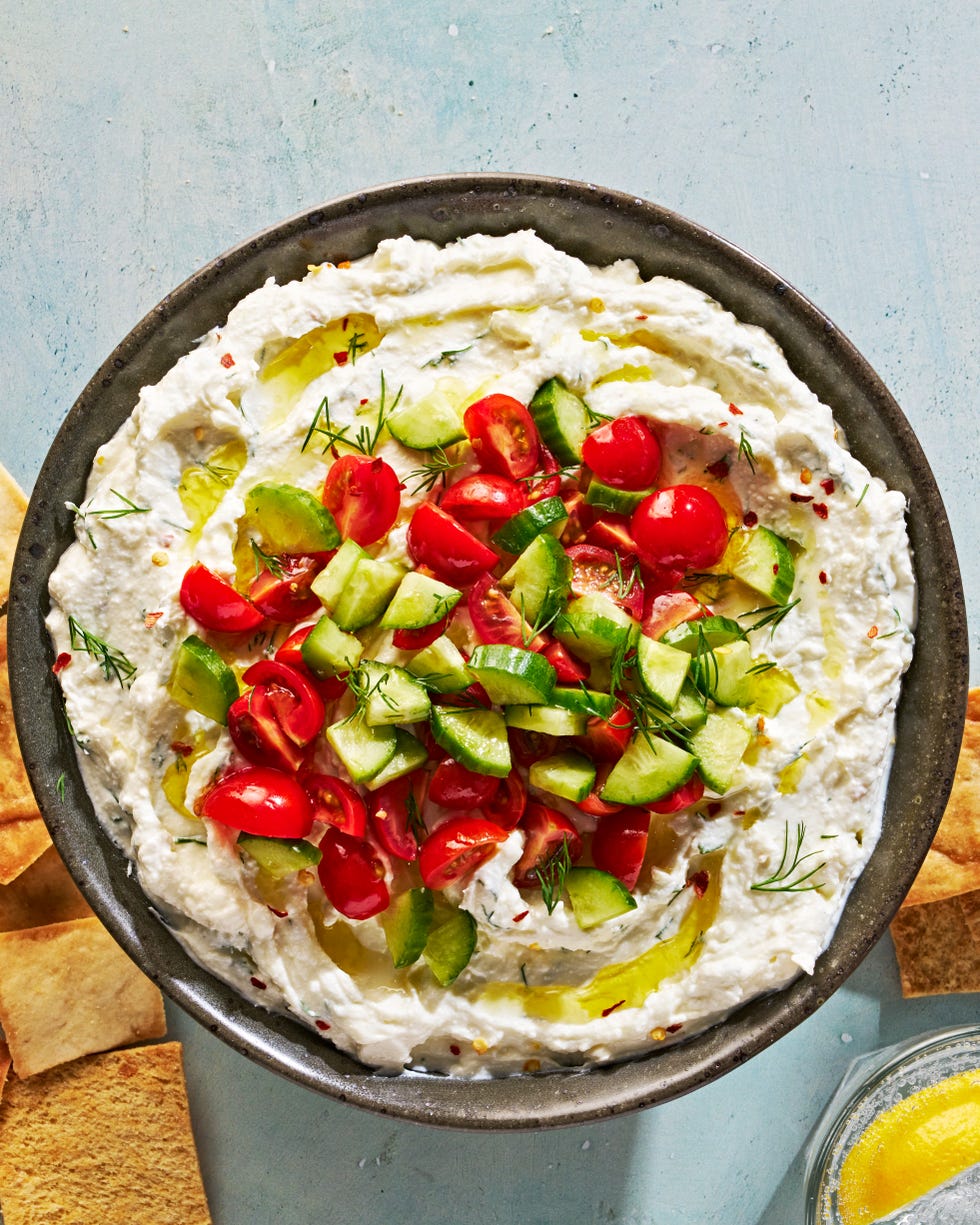 feta dip in a bowl topped with tomatoes and cucumber
