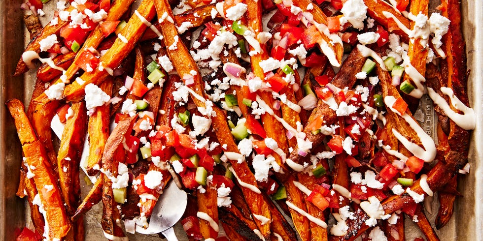 sweet potato fries topped with tomato and cucumber salad, tahini drizzle and feta