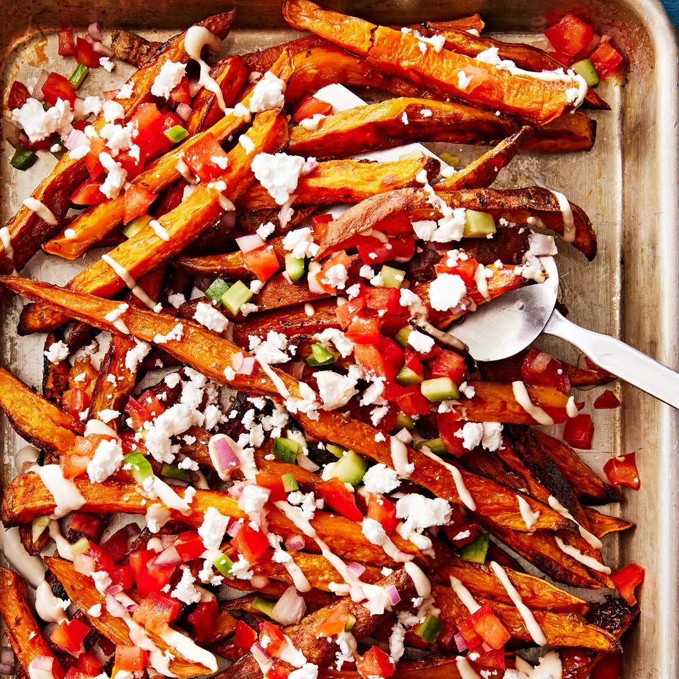 sweet potato fries topped with tomato and cucumber salad, tahini drizzle and feta