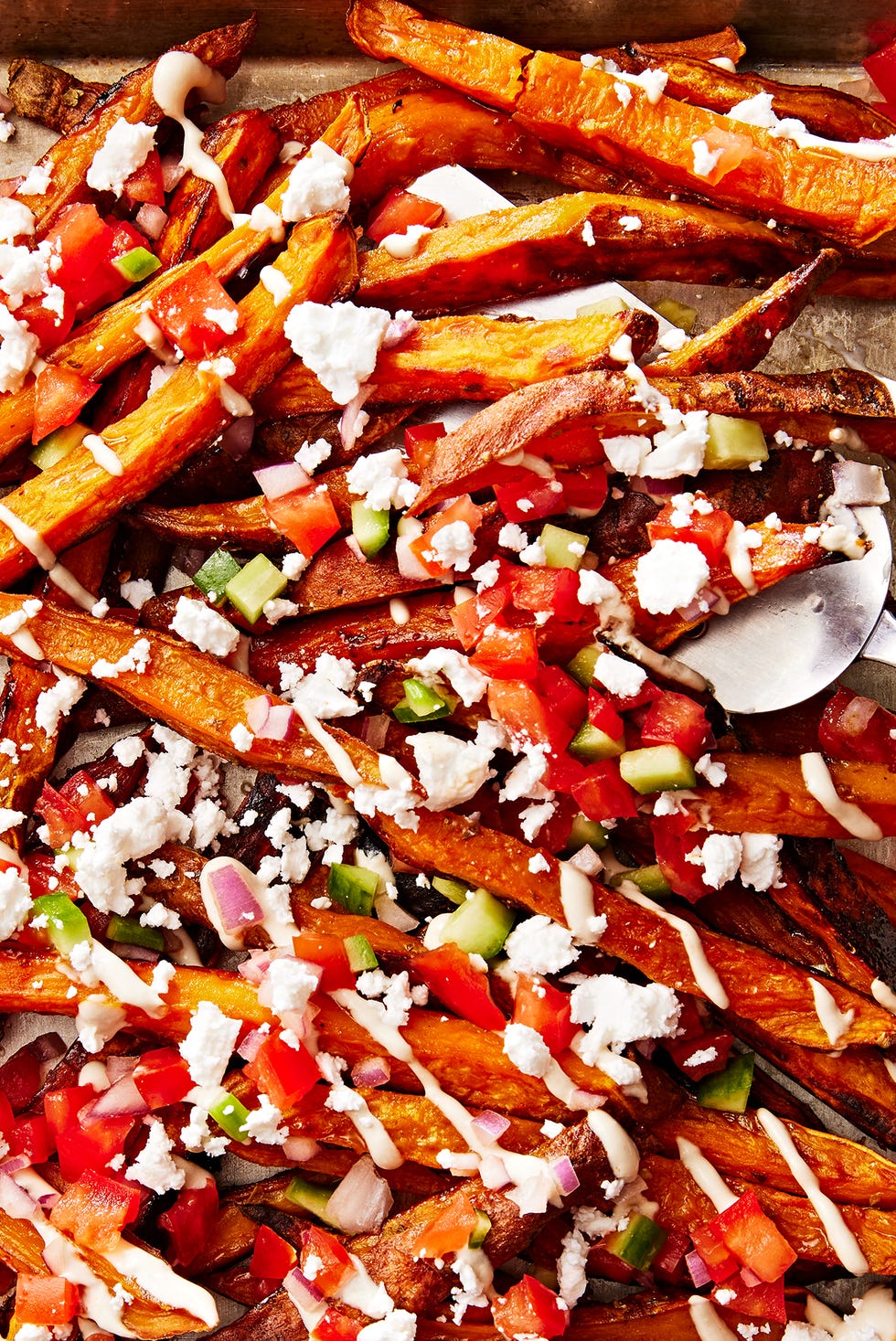 Loaded Mediterranean Sweet Potato Fries sweet potato fries topped with tomato and cucumber salad, tahini drizzle and feta
