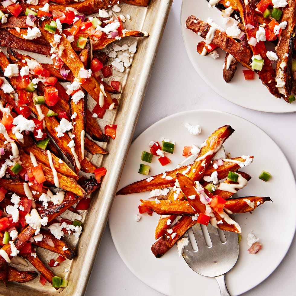 sweet potato fries topped with tomato and cucumber salad, tahini drizzle and feta