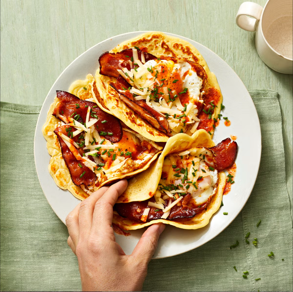 pancake tacos with bacon, egg, and cheese on a white plate