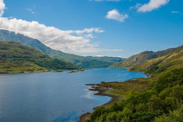 view of a scottish lake under blue skies with white clouds in summertime, loch lomond, argyll bute, scotland, uk, europe