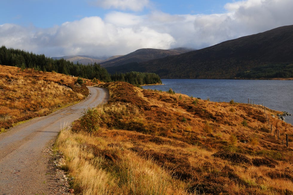 a road runs next to loch ossian, with mountains in the background