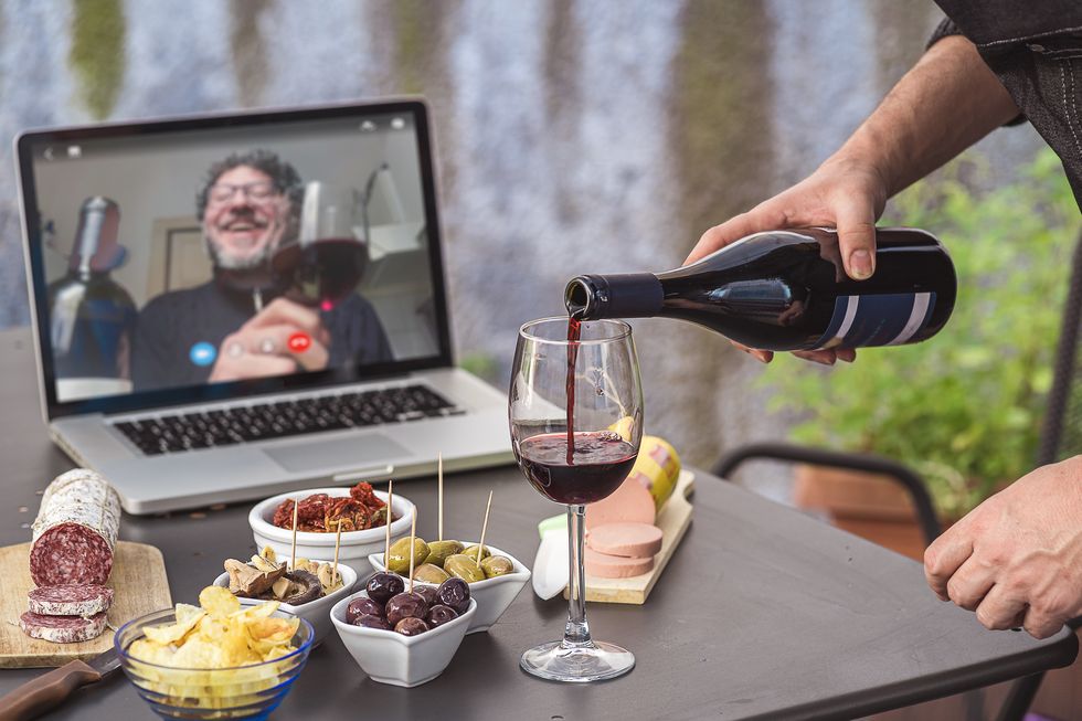 lockdown aperitif video call party adult men are making a pre meal aperitif with snacks, wine, and italian appetizers together at home using teleconference platform apps during covid 19 restrictions