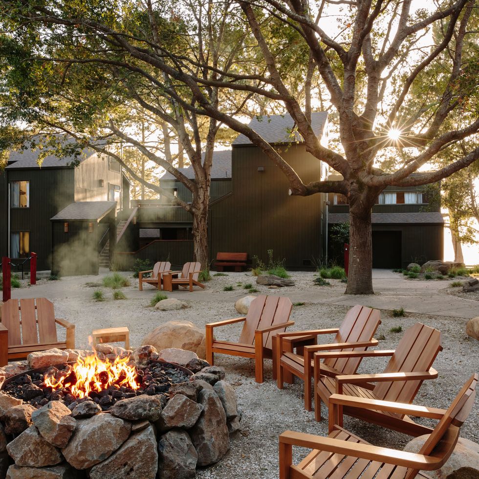 a fire pit with chairs and a fire pit in a yard with trees
