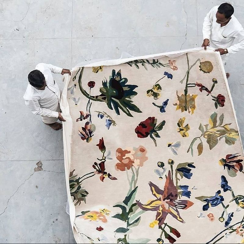 2 people holding length of patterned rug