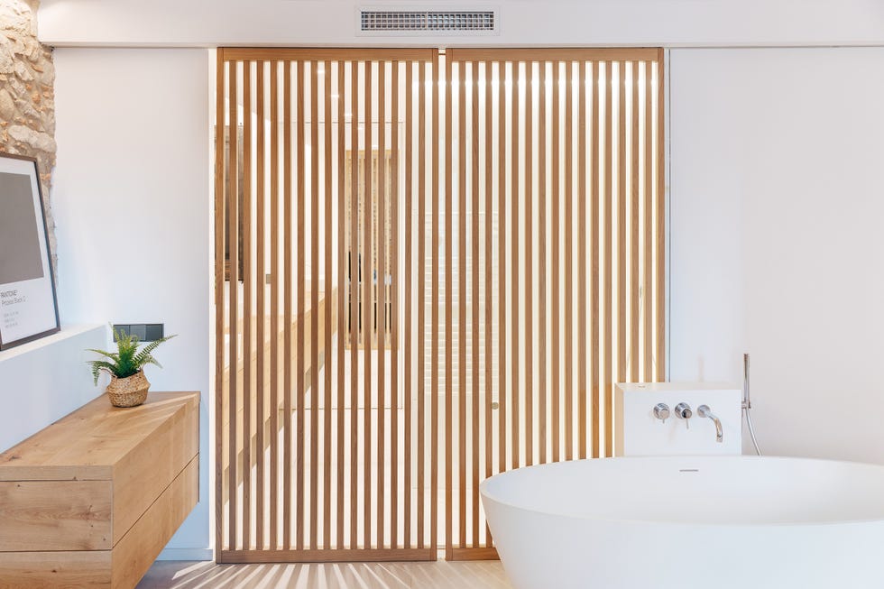 baño con bañera exenta y puerta corredera con lamas de madera