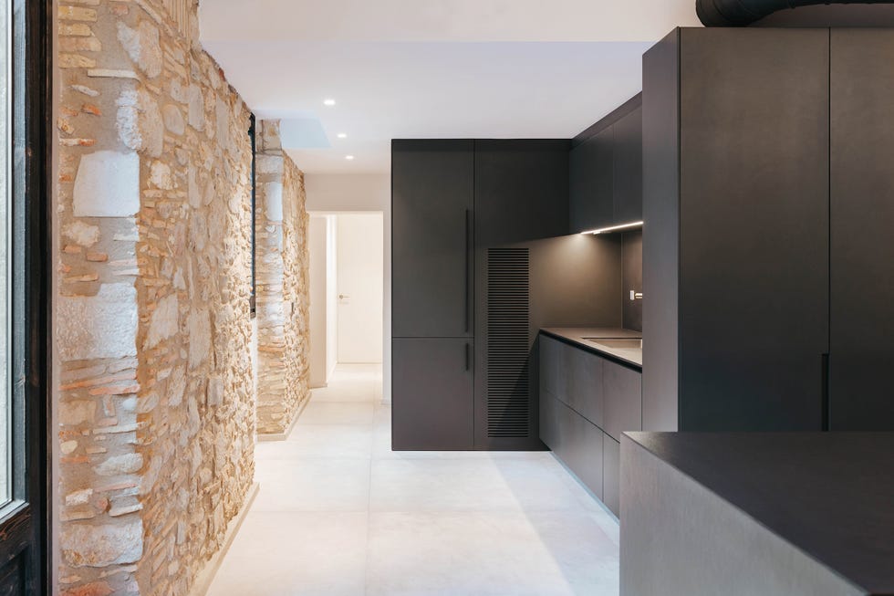 cocina de estilo industrial con isla central y paredes de piedra vista