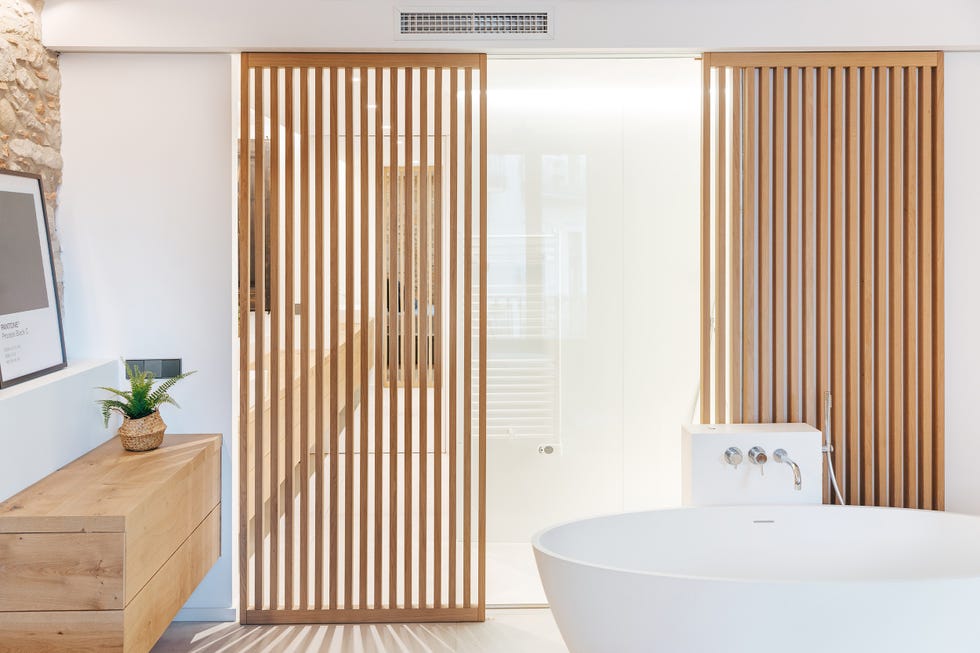 baño con bañera exenta y puerta corredera con lamas de madera