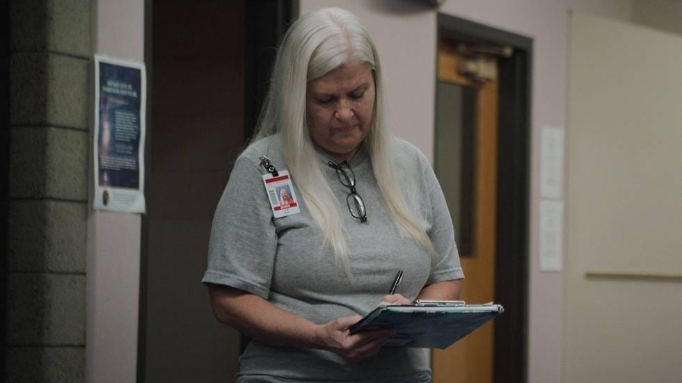 lois riess looking down as she signs a clipboard