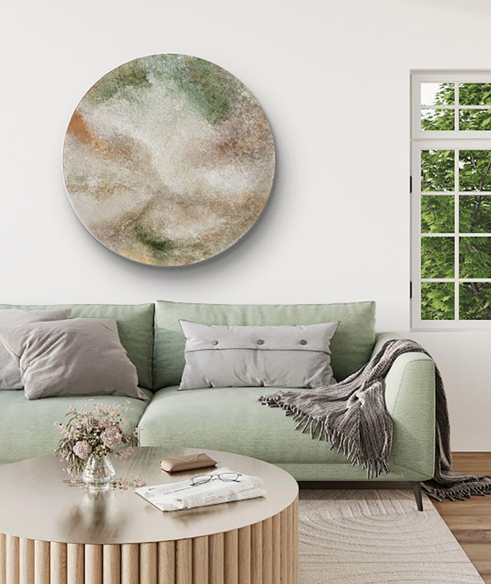 lola castillejos cuadro circular asbtracto sobre un sofa verde y una ventana a la derecha