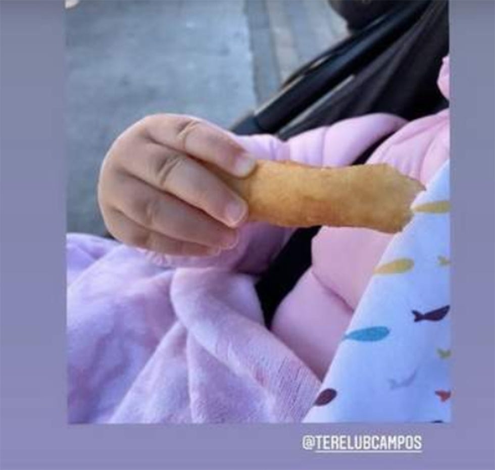 lola, hija de toñi moreno, con un churro en la mano
