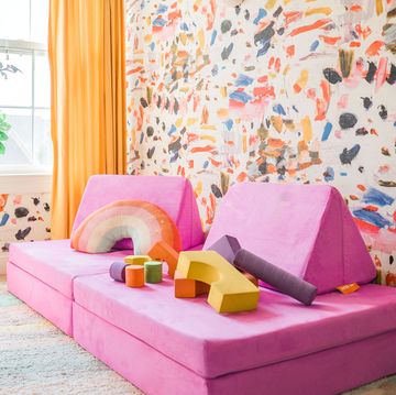 the nugget play couch for kids, in pink next to brightly colored wallpaper, reviewed by good housekeeping