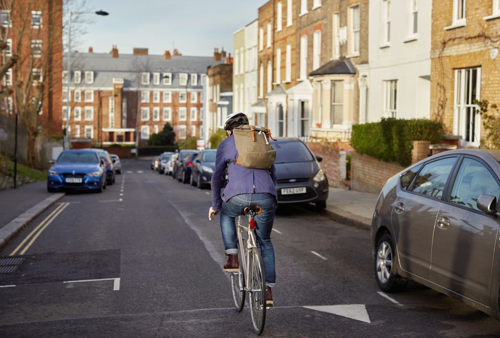 london cycle commuter riding down street in neighborhood on way to work