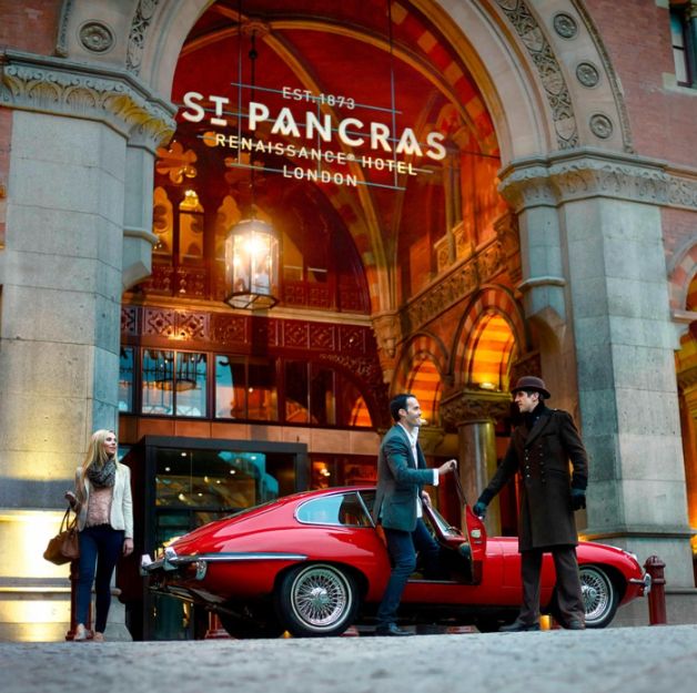 a red car parked in front of a building with a sign on it at st pancras renaissance