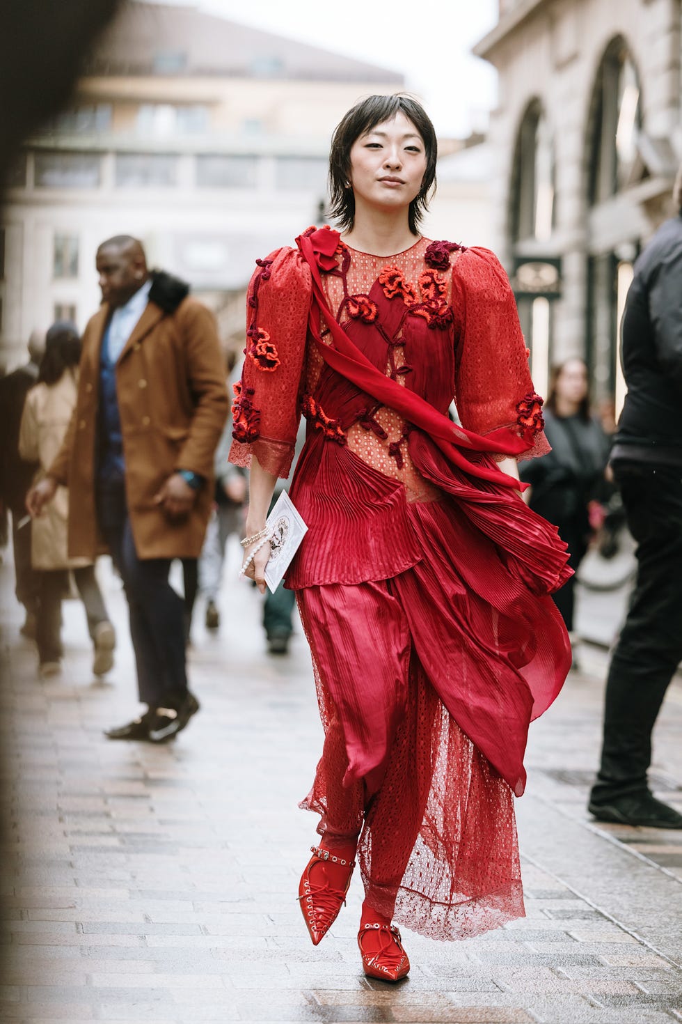 fashionable person walking in a vibrant red outfit best fringe hair at london fashion week