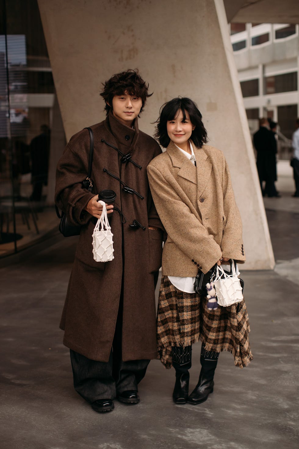 two individuals posing together in fashionable outfits in an urban setting best fringe hair at london fashion week