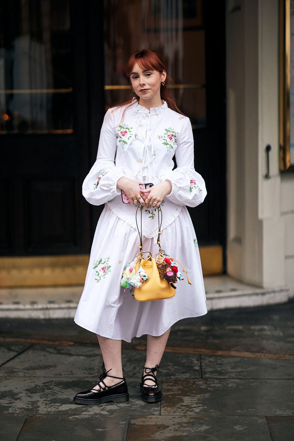 fashionable individual wearing a white floral dress and unique accessories best fringe hair at london fashion week