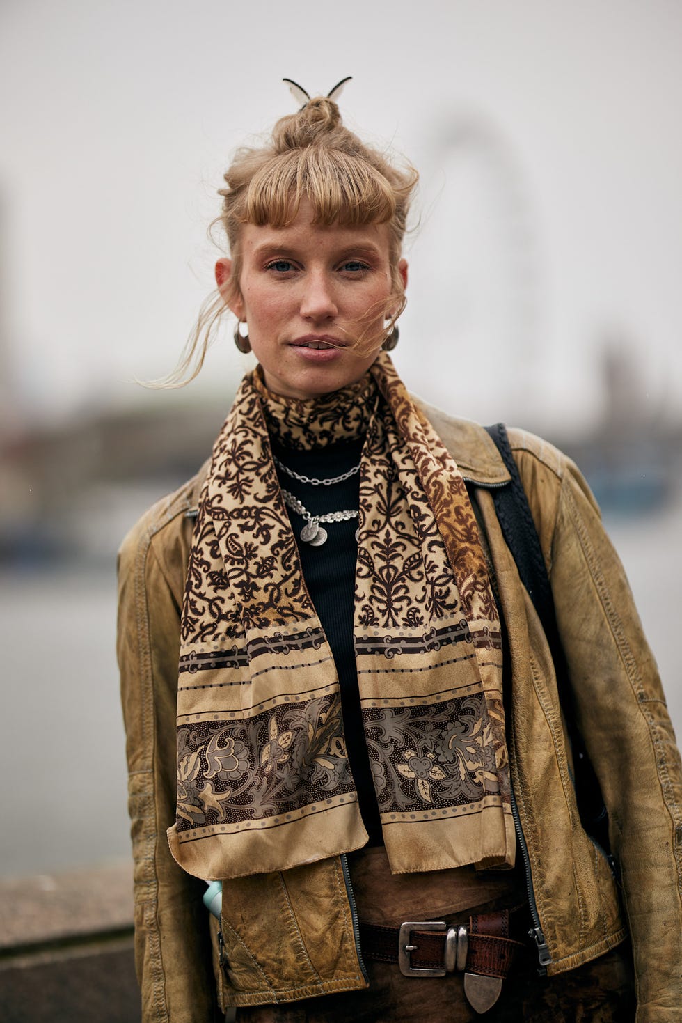 outdoor portrait featuring a person wearing a patterned scarf and leather jacket best fringe haircuts london fashion week